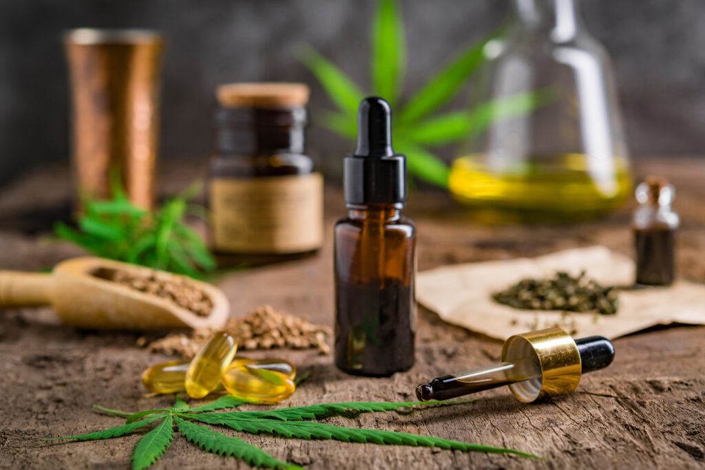 hemp essential oil in small glass bottle. container with cannabis leaves and cannabis seeds on wooden.