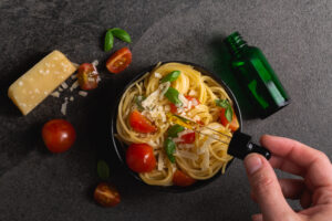 Cannabis CBD spaghetti pasta overhead food photography on black background. Made with CBD infused marijuana oil. Cannabis edibles for medication or recreational enjoyment of weed. 